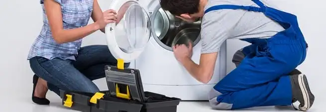 Washer repair technician inspecting a front-load washing machine with tools in Wichita, KS