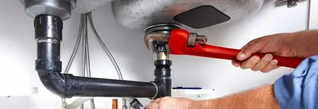Garbage disposal repair technician tightening the sink drain and disposal connection in Wichita, KS