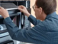 Appliance repair technician replacing a microwave vent filter in Wichita, KS
