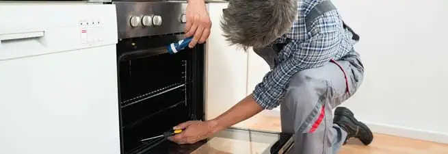 Oven repair technician inspecting and servicing an electric oven in Wichita, KS