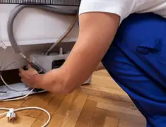Appliance repair technician fixing refrigerator water line and connections in Wichita, KS