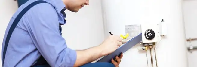 Water heater repair technician inspecting the unit and recording service notes in Wichita, KS