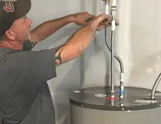 Water heater repair technician tightening supply line connections in Wichita, KS