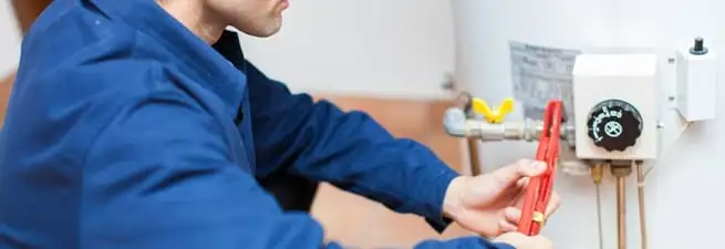 Water heater repair technician adjusting the temperature control and gas valve in Wichita, KS